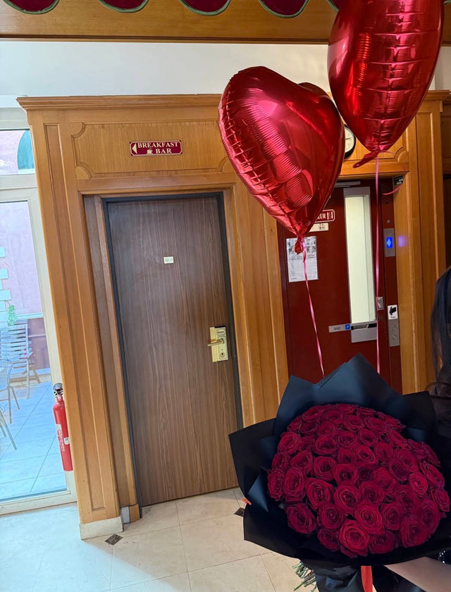 Bouquet de roses rouges et ballons cœur remis à l'arrivée